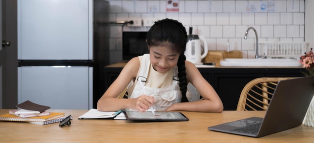 École à la maison Petite jeune fille asiatique apprenant un cours en ligne d'un enseignant par une application de réunion sur Internet à distance en raison de la pandémie de coronavirus Enfant regardant un écran d'ordinateur portable cette femme enseignant