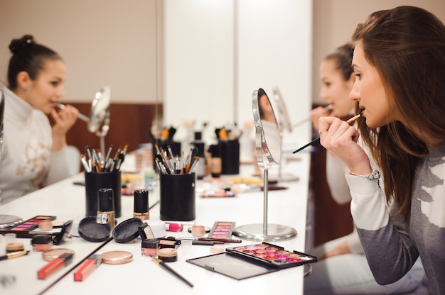 École de maquillage. Maquilleuse faisant le maquillage professionnel de la jeune femme. Beauté shcool