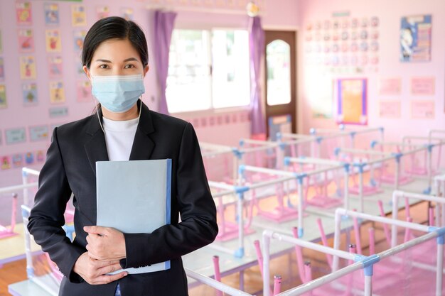 École de récréation pour enfants Et les jeunes professeurs asiatiques portent des masques pour empêcher la propagation du COVID 19 dans une salle de classe sans élèves.