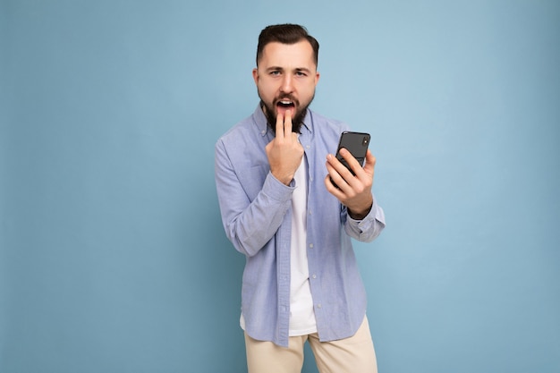 En colère furieux beau beau jeune homme mal rasé brune avec barbe vêtu d'un blanc décontracté