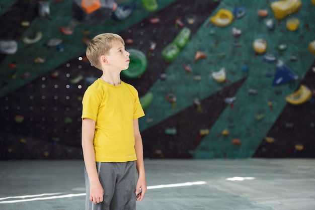 Écolier actif contemporain en t-shirt jaune et pantalon gris debout dans le centre sportif