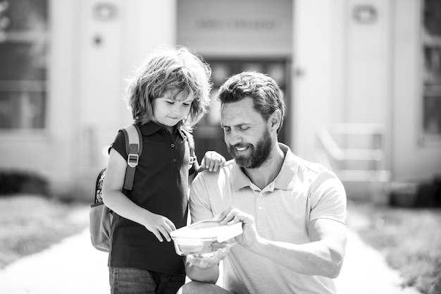 Écolier allant à l'école avec le père écolier et le parent en chemise tenant la boîte à lunch déjeuner scolaire