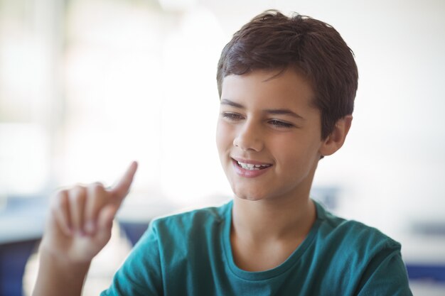 Écolier attentif faisant des gestes en classe