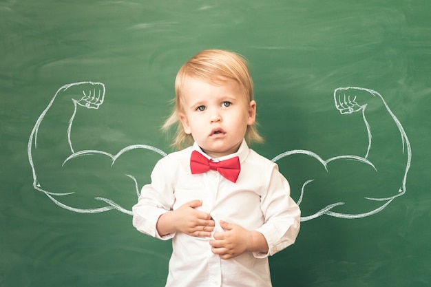 Écolier en classe. Enfant heureux contre le tableau vert. Notion d'éducation