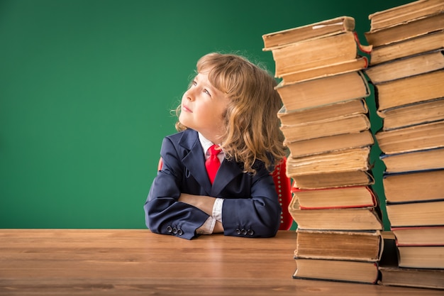 Écolier en classe. Enfant heureux contre le tableau vert. Notion d'éducation