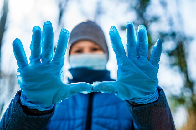 Écolier dans des gants en caoutchouc médicaux et un masque facial