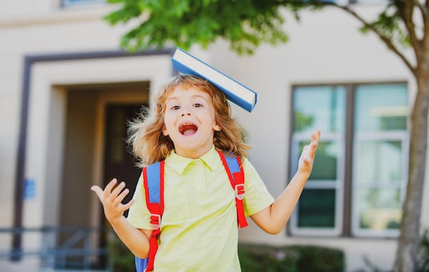 Écolier drôle excité avec un livre à l'école