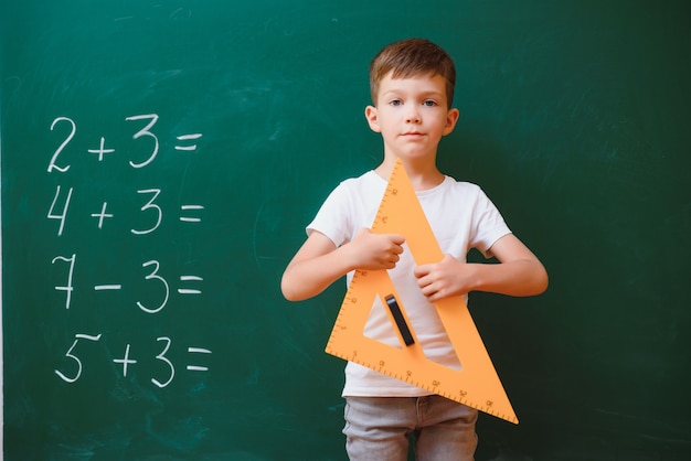 Écolier drôle près de la commission scolaire verte dans la salle de classe. École primaire. Retour à l'école.