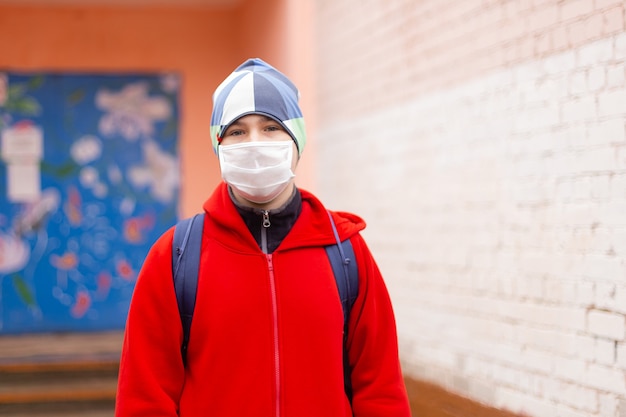 Écolier garçon sort de l'école avec un masque de protection