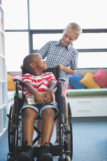 Écolier heureux portant son ami en fauteuil roulant