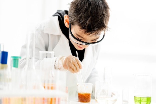 Écolier portant des lunettes de protection faisant une expérience de chimie dans une classe de sciences élémentaire et mélanger des composants Élève intelligent en laboratoire pendant le test