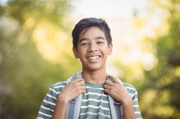 Écolier souriant debout avec cartable sur le campus