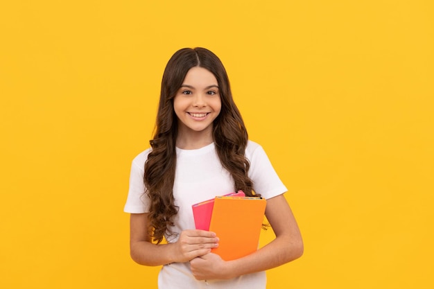 Écolier souriant prêt à étudier avec un cahier d'exercices, à l'école.