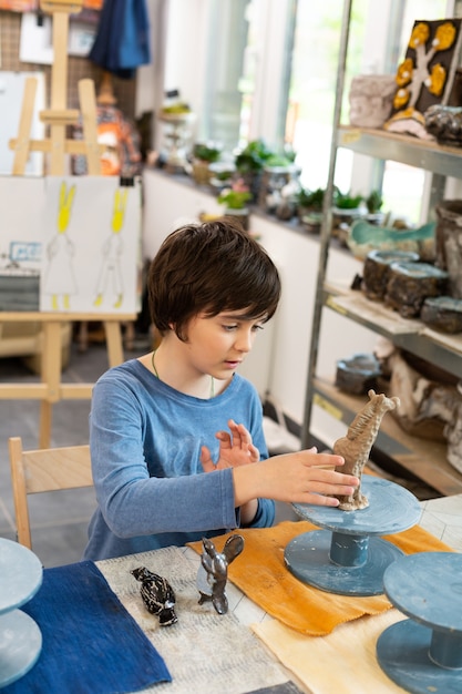 Écolier talentueux sculptant des figures d'argile à l'école d'art