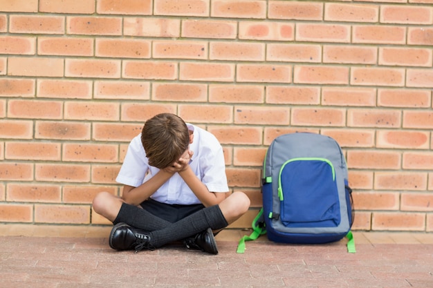 Écolier triste assis seul dans le couloir