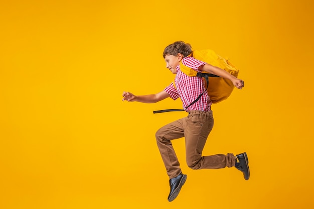 Écolier en uniforme avec un sac à dos sautant