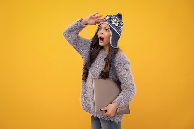 Écolière adolescente excitée Vacances scolaires d'automne Retour à l'école Écolière adolescente en vêtements d'automne tenir un ordinateur portable sur fond de studio isolé jaune