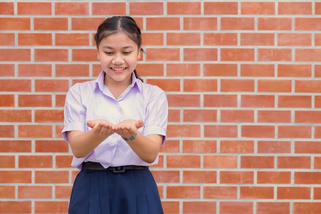 Écolière asiatique regardant deux paumes chose étonnante dans la main montrer le concept d'éducation actuel