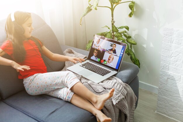 Écolière assez élégante étudiant les devoirs en maths pendant sa leçon en ligne à la maison, distance sociale pendant la quarantaine, auto-isolement, concept d'éducation en ligne, élève à domicile