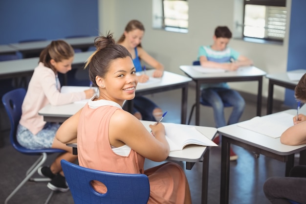 Écolière assise au bureau en classe