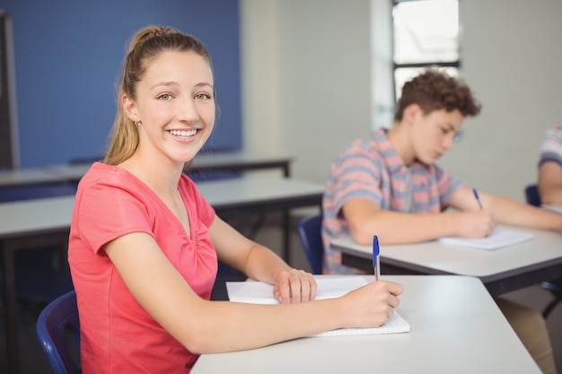 Écolière assise au bureau en classe