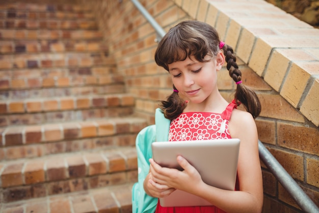 Écolière brune à la recherche de sa tablette numérique