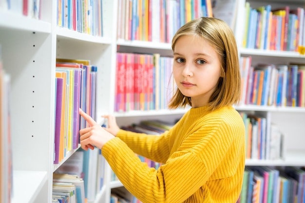 Écolière choisissant un livre dans la bibliothèque de l'école