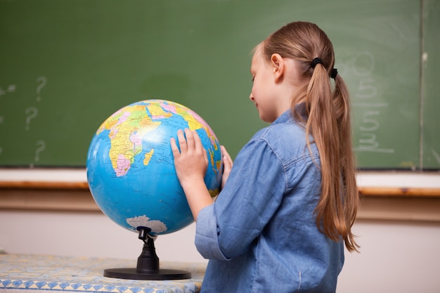 Écolière concentrée regardant un globe