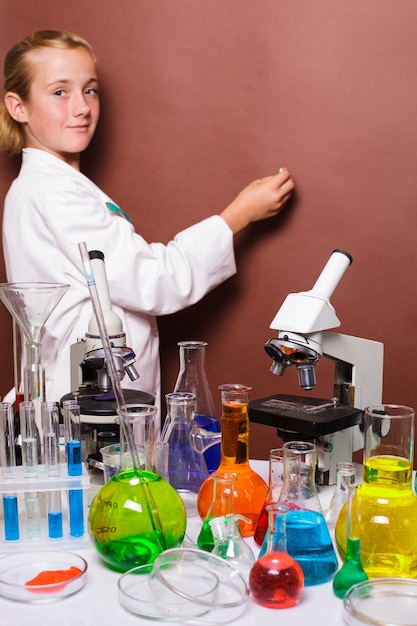 Écolière à la craie debout près du tableau noir dans les cours de laboratoire en chimie et veut blanc. Focus sur le microscope