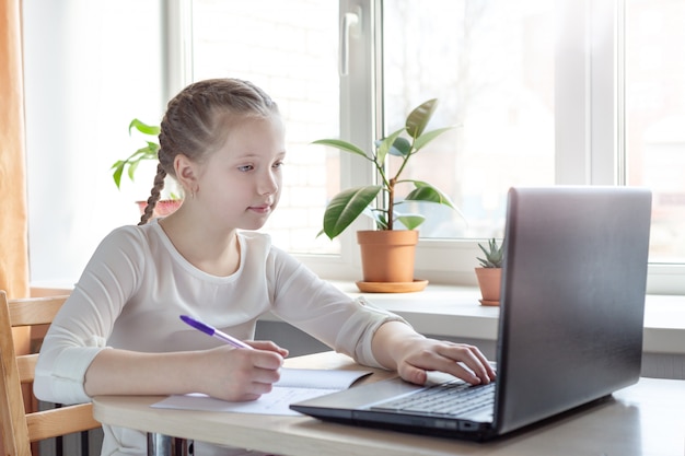 Écolière étudie à la maison à l'aide d'un ordinateur portable. École à domicile, enseignement en ligne, enseignement à domicile