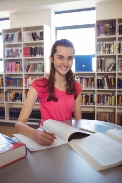 Écolière à faire ses devoirs en bibliothèque à l'école