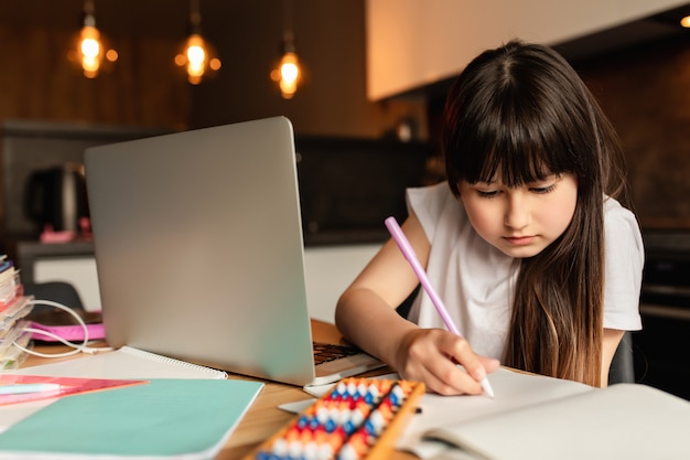 Écolière fait ses devoirs à la maison. Apprentissage en ligne avec un ordinateur portable. Étudiez avec un appel vidéo. Enseignement à distance pendant la quarantaine