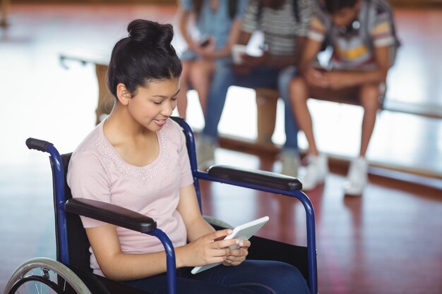 Écolière handicapée à l'aide de tablette numérique avec des camarades de classe en arrière-plan