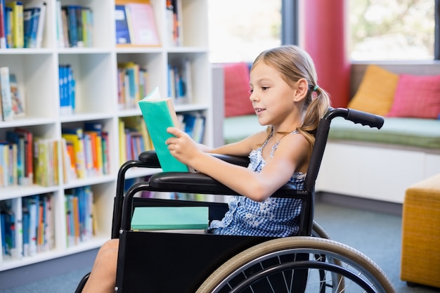 Écolière handicapée livre de lecture dans la bibliothèque