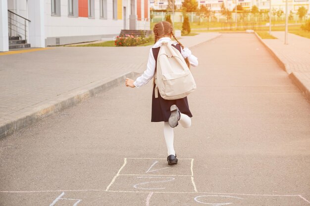 Écolière junior jouant à la marelle dans la cour de l'école