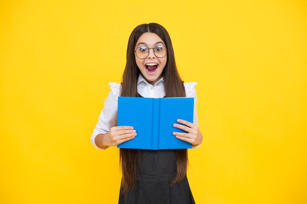 Écolière avec livre de copie posant sur fond isolé Leçon de littérature lycée Lecteur d'enfant intellectuel Visage excité émotions joyeuses d'une adolescente