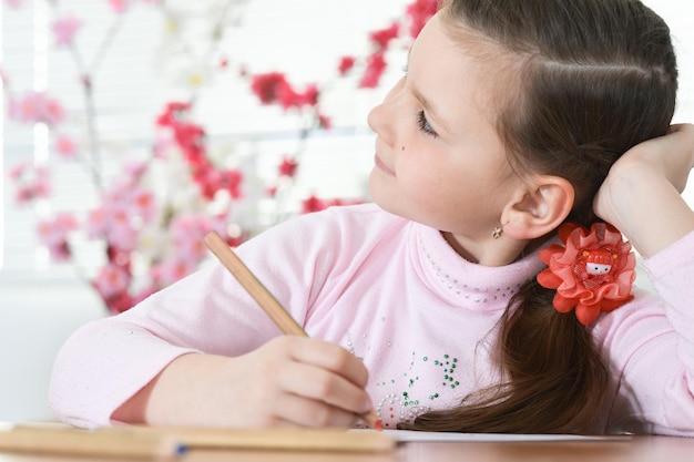 Écolière mignonne assis à table et dessin