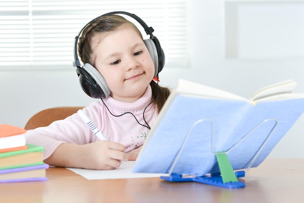 Écolière mignonne assise à table et faisant ses devoirs