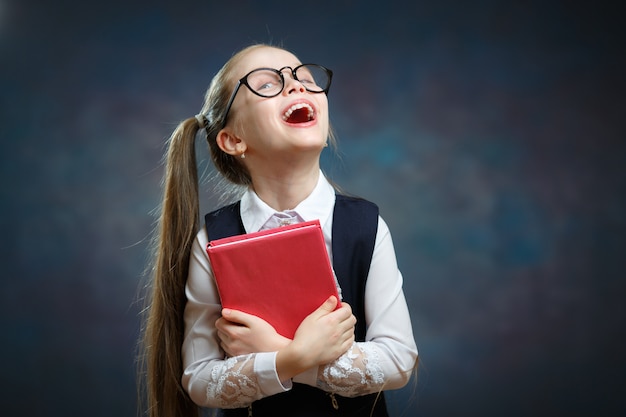 Écolière mignonne avec la bouche ouverte tenir le livre serré