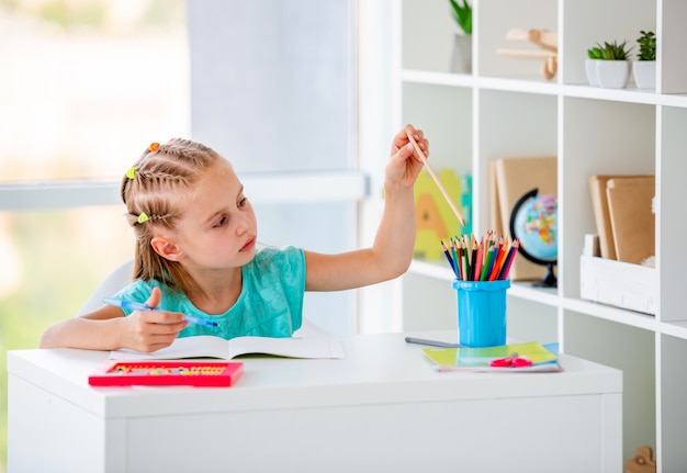 Écolière mignonne avec des cheveux tressés au bureau