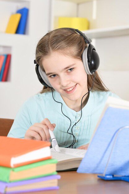 Écolière mignonne dans des écouteurs étudiant à la maison