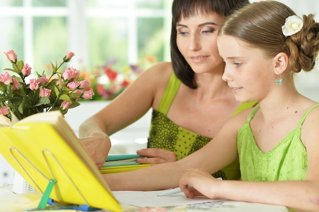 Écolière mignonne faisant ses devoirs avec sa mère à la maison