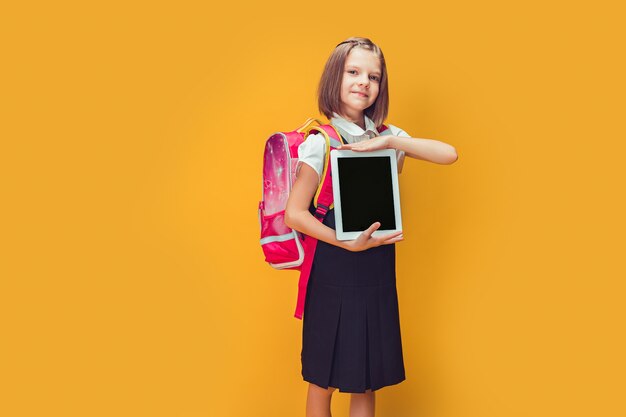 Écolière mignonne se préparant à aller à l'école avec sac à dos montrant le concept de retour à l'école de la tablette