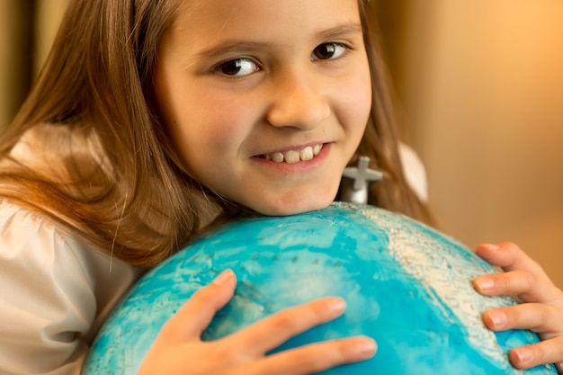 Écolière mignonne tenant le grand globe terrestre