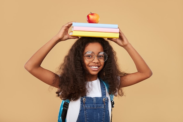 Écolière noire futée avec des manuels et une pomme