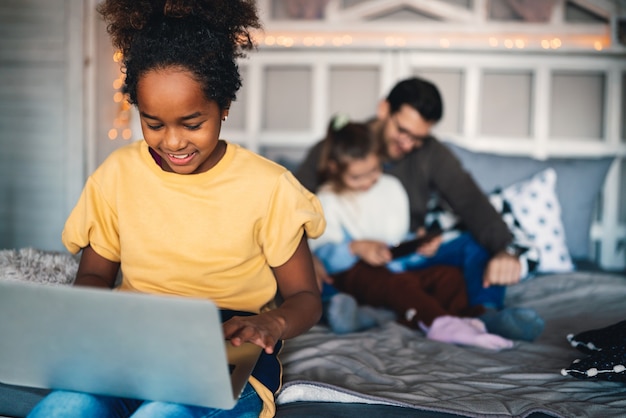 Écolière préadolescente intelligente faisant ses devoirs avec un cahier numérique à la maison. Enfant utilisant des gadgets pour étudier. Éducation et apprentissage pour les enfants.