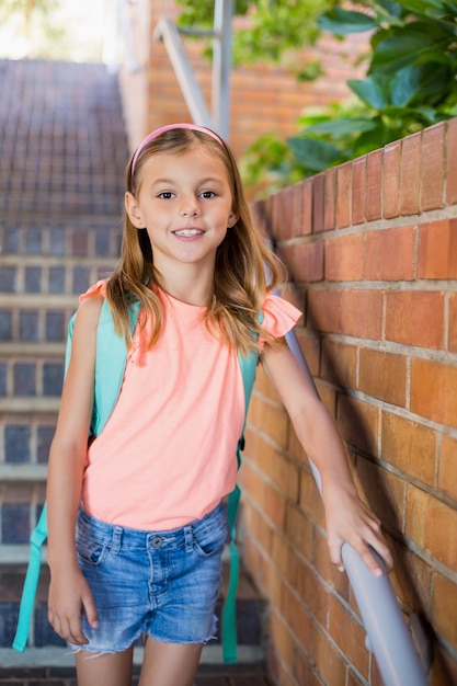 Écolière souriante debout sur l'escalier