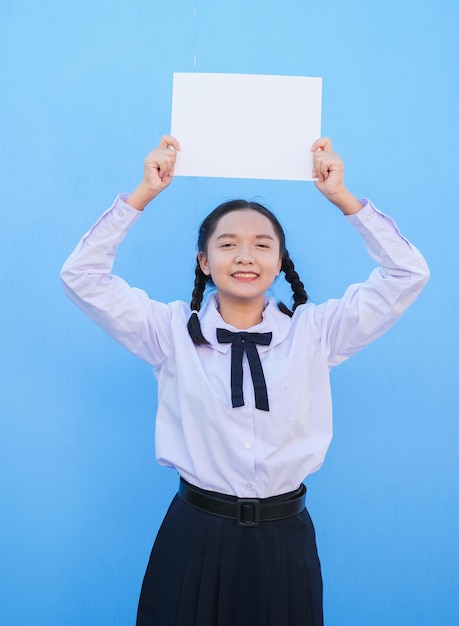Écolière tenant un panneau d'affichage sur fond bleu
