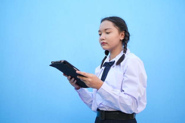 Écolière tenant une tablette sur fond bleu