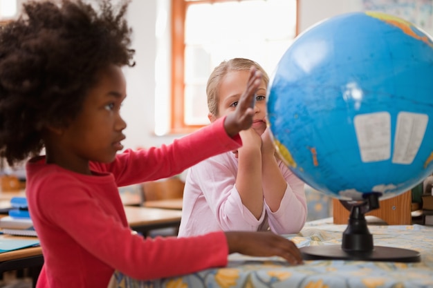Écolières heureux en regardant un globe